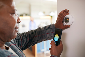 Homeowner looking at thermostat and app on phone